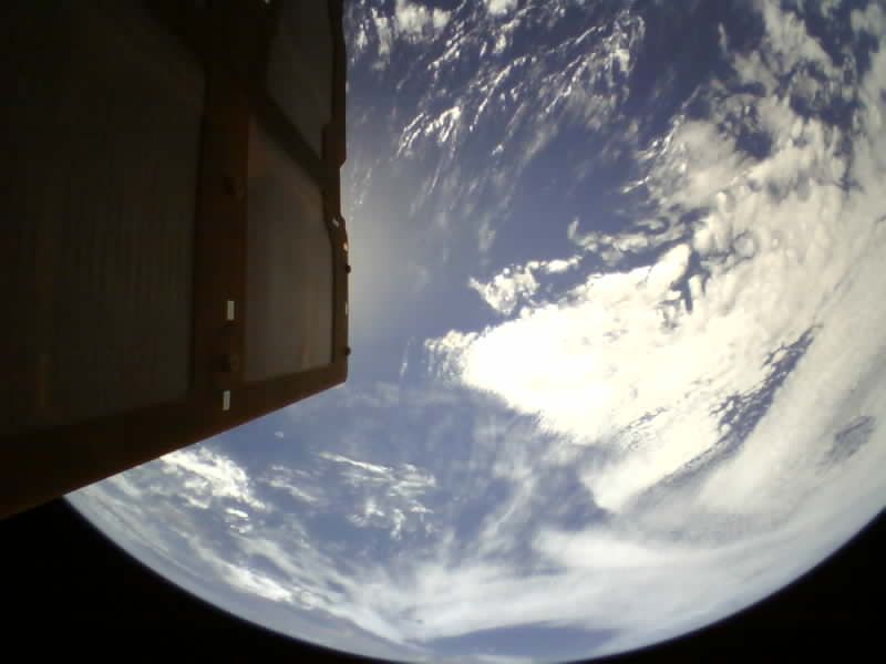 Earth seen from Gama Alpha in orbit, with one of the spacecraft's solar panels in the foreground.